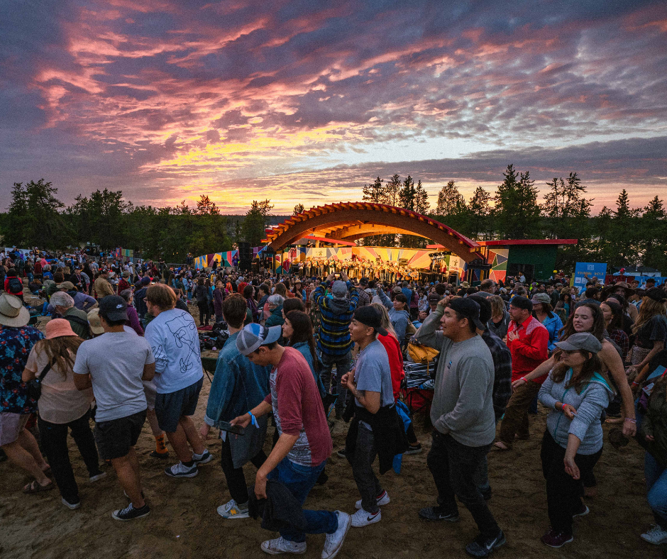 festival goers dancing in front of stage under the Midnight Sun